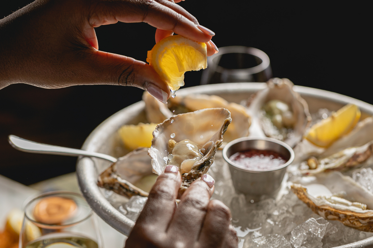 Lemon being squeezed onto an oyster 